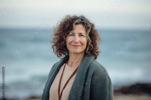 Portrait of smiling mature woman standing on the beach in autumn.