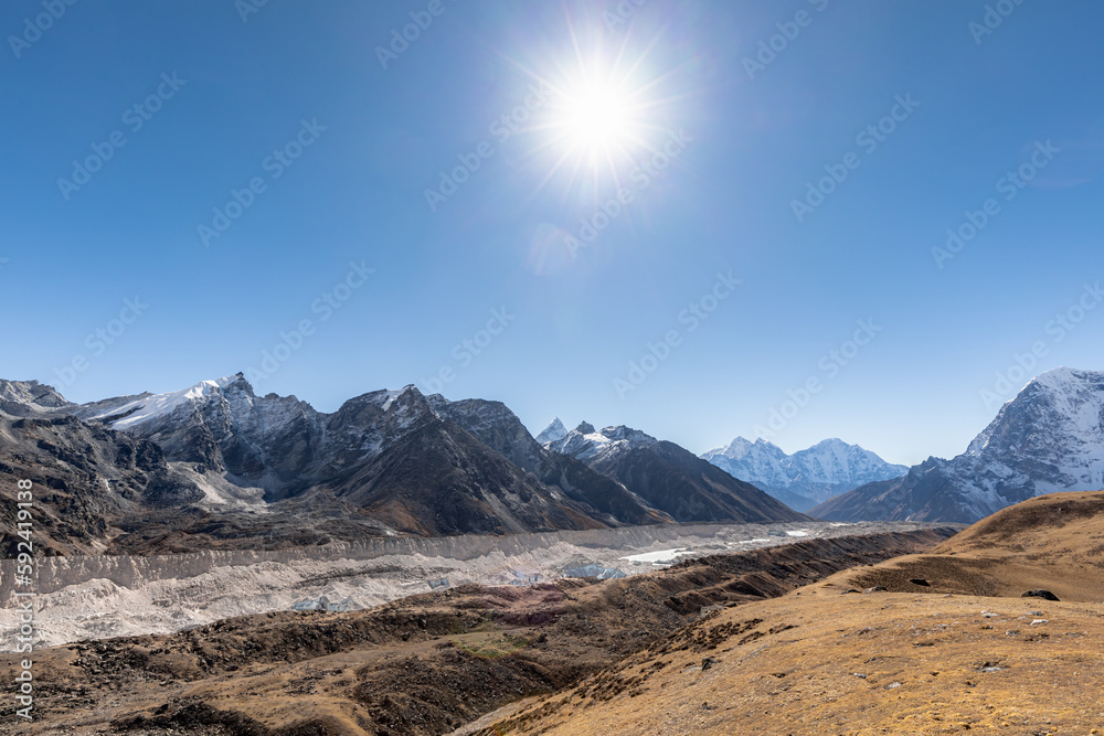 Khumbu glacier slowly flowing from the slopes of Mount Everest down to the valley with noon sun above