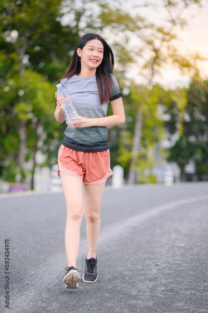 attractive asian woman healthy jogging exercise with transparent plastic water bottle in park outdoor at the evening attractive asian woman healthy jogging exercise with transparent plastic water bottle in park outdoor at the evening