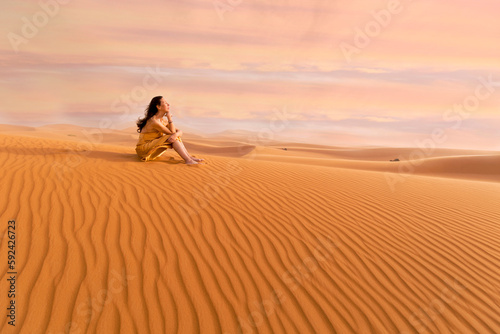 woman in yellow dress playing with the wind in the desert II