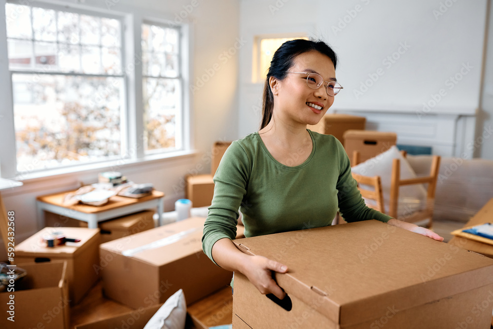 Young Asian woman carrying carton box after moving into new home. Young Asian woman carrying carton box after moving into new home.