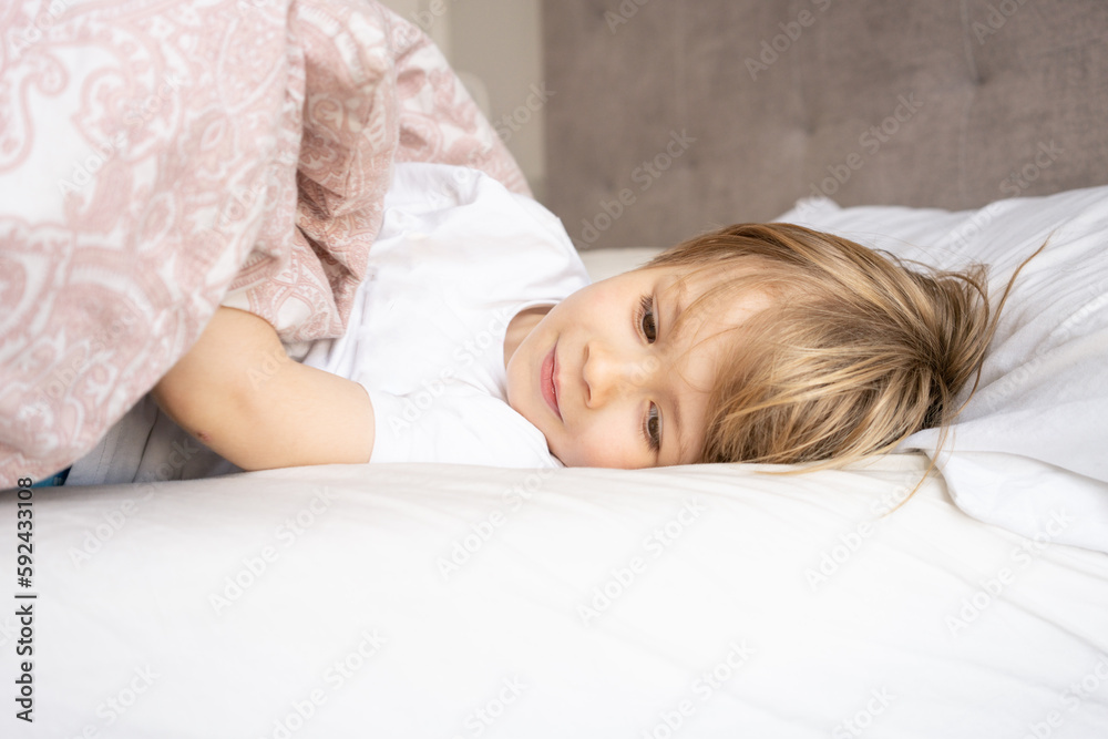 boy child is lying in bed under a blanket and does not want to sleep , insomnia and fun boy child is lying in bed under a blanket and does not want to sleep , insomnia and fun