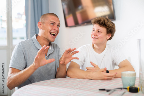 Father and his young son talking about something funny while sitting at the table