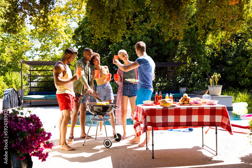Happy diverse group of friends having pool party, barbecuing in garden