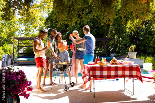 Foto Happy diverse group of friends having pool party, barbecuing in garden