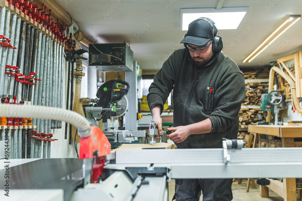 Adult male carpenter is using a circular saw to cut wood to construct new project. Freelance blue collar job concept. High quality photo Adult male carpenter is using a circular saw to cut wood to construct new project. Freelance blue collar job concept. High quality photo