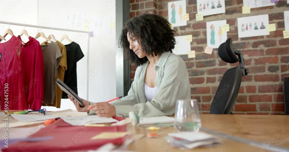 Portrait of happy biracial asian female designer using tablet in fashion design studio, slow motion Portrait of happy biracial asian female designer using tablet in fashion design studio, slow motion