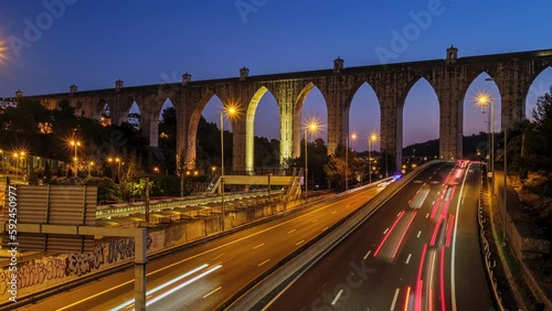 Time-lapse of highway traffic near Campolide station with Aguas Livres Aqueduct in the background in the evening with car lights trails. Lisbon, Portugal. Zoom in effect photo