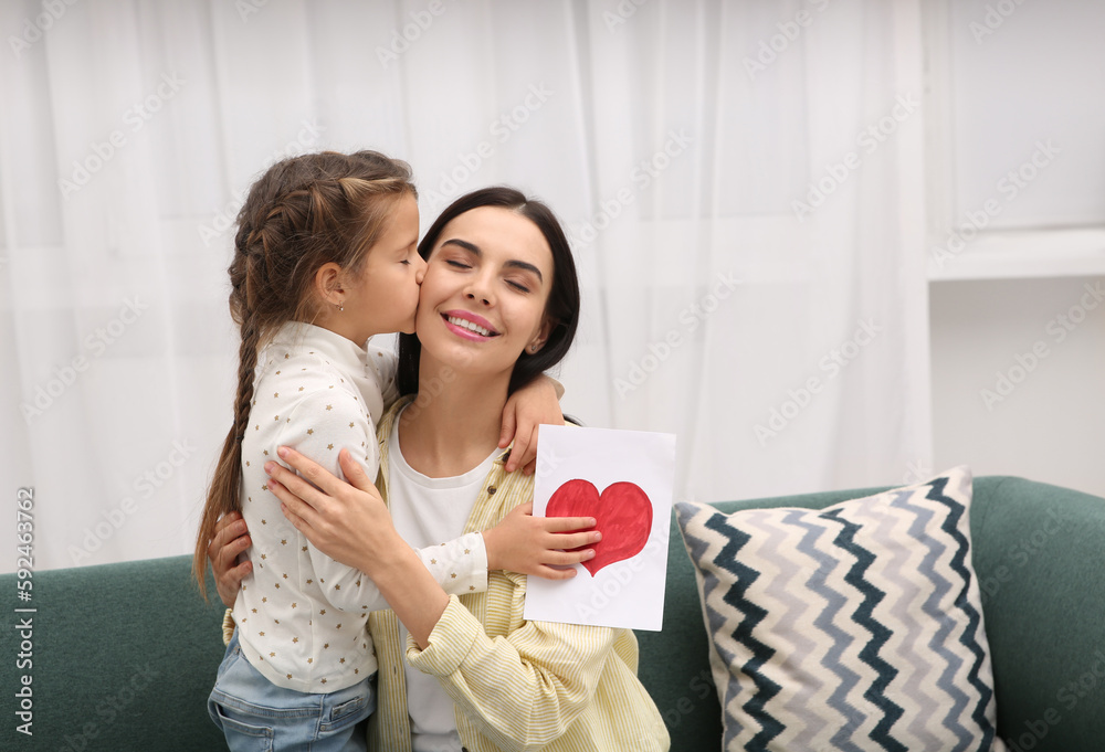 Happy woman with her daughter and handmade greeting card on sofa at home, space for text. Mother's day celebration Happy woman with her daughter and handmade greeting card on sofa at home, space for text. Mother's day celebration