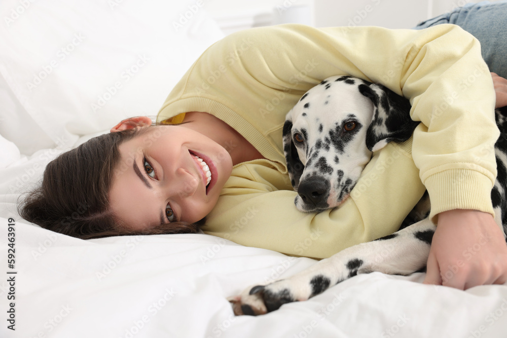 Beautiful woman with her adorable Dalmatian dog on bed at home. Lovely pet Beautiful woman with her adorable Dalmatian dog on bed at home. Lovely pet