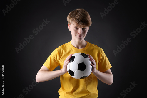 Teenage boy with soccer ball on black background © New Africa