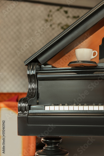 Cup with coaster on black grand piano in cafe