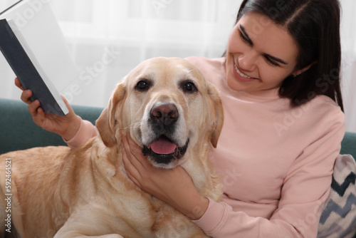 Happy woman sitting with cute Labrador Retriever on sofa at home