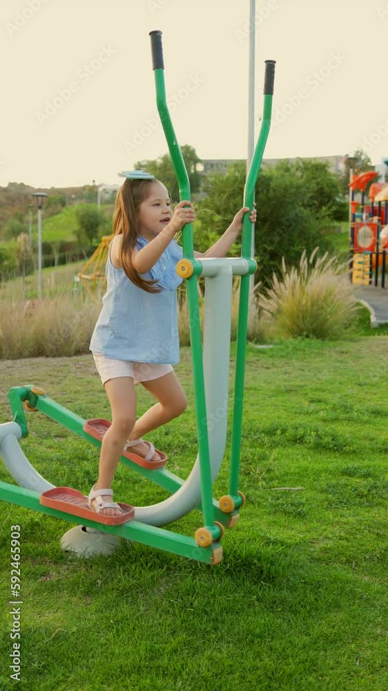 Niña hermosa latina rubia jugando a hacer ejercicio en el parque al aire libre disfrutando y divertida en un hermoso día soleado al atardecer en los aparatos 