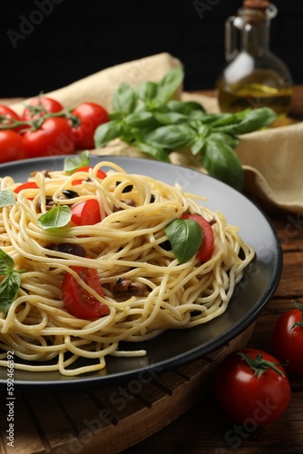 Delicious pasta with anchovies, tomatoes and basil on wooden table