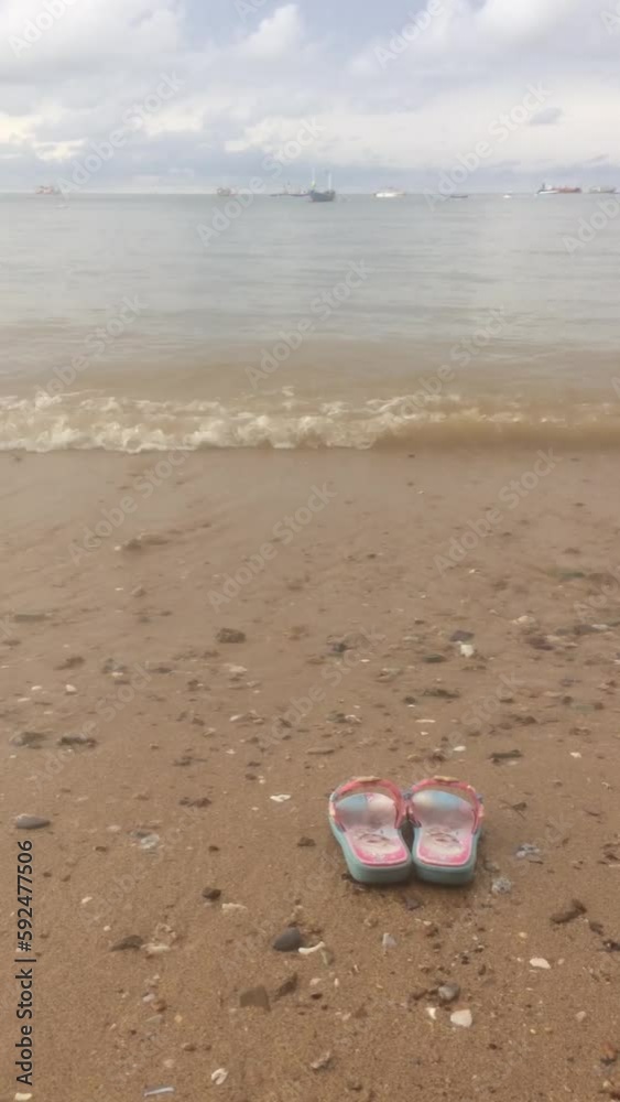 sandals on the beach, Pink baby sandal isolated on the beach, The waves gently crash against the beach. sandals on the beach, Pink baby sandal isolated on the beach, The waves gently crash against the beach.