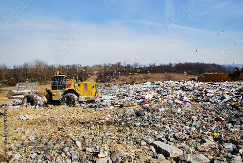 Large polluted landfill with a bulldozer that is leveling garbage
