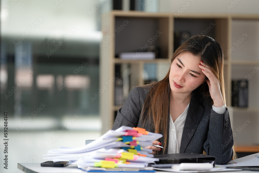 Sad Asian woman looking annoyed and stressed, sitting at the desk, using a laptop, thinking, feeling tired and bored with depression problems Sad Asian woman looking annoyed and stressed, sitting at the desk, using a laptop, thinking, feeling tired and bored with depression problems