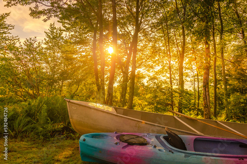Fototapeta Naklejka Na Ścianę i Meble -  A kayak and canoe in front of trees with sunset