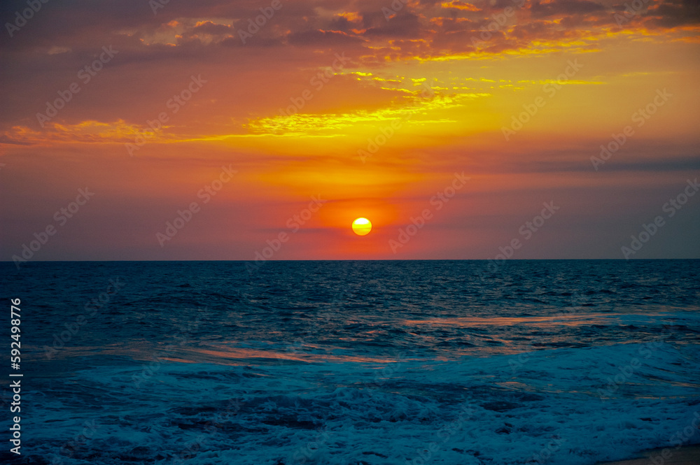 Sunset on black sand beach in Guatemala, tropical sunset full of color and waves.