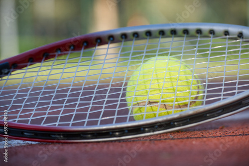 Tennis racquet and yellow tennis ball on outdoor court © NetPix
