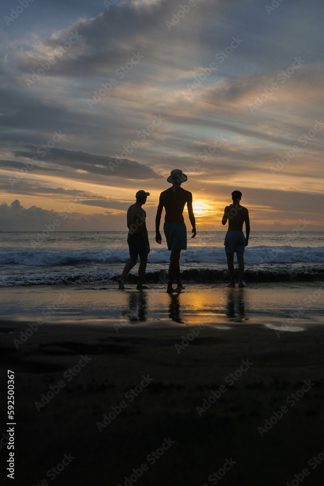 Trois amis devant un coucher de soleil sur une plage de l'île de la Réunion.