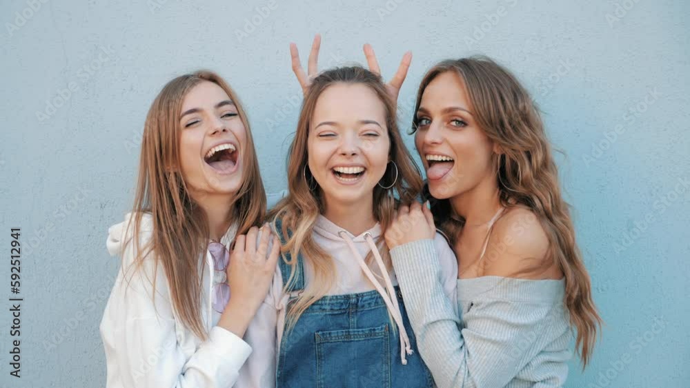 Three young female hipster friends. girls dressed in summer jeans shorts. Women smiling. Having fun and going crazy. Models posing in the street at sunset. Three young female hipster friends. girls dressed in summer jeans shorts. Women smiling. Having fun and going crazy. Models posing in the street at sunset.