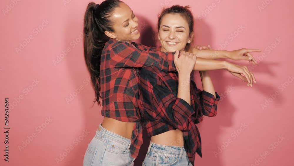 Two young beautiful smiling brunette female in trendy summer clothes. Lovely women posing on in studio. Positive models having fun. Cheerful and happy. isolated Two young beautiful smiling brunette female in trendy summer clothes. Lovely women posing on in studio. Positive models having fun. Cheerful and happy. isolated