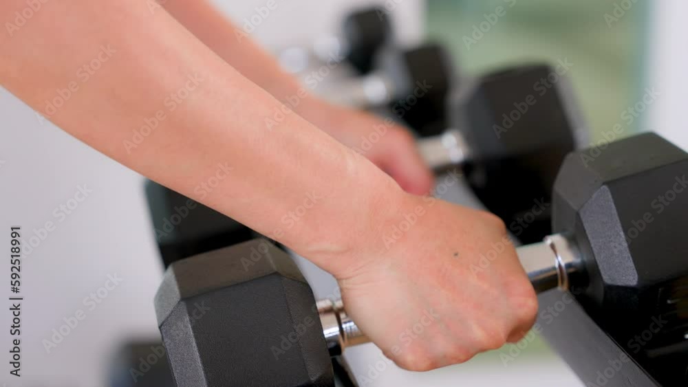 Black dumbbell row set. Hand pickup metal dumbbells on rack in sport