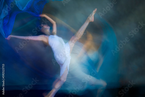 Mystical, blurry dance photo of adult woman with floating blue fabric.