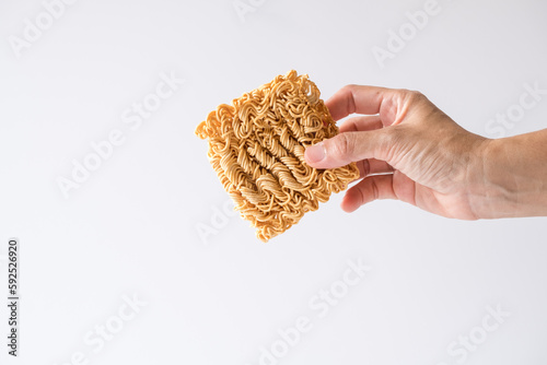 Close up hand holding Instant noodles, a dried and precooked noodle block with white background.