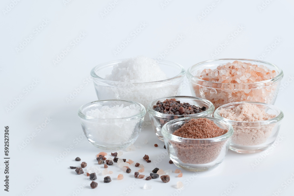 Variety of different flake flower sea salt, Himalayan black salt and pink Himalayan with rosemary for cooking or spa on white background. Variety of different flake flower sea salt, Himalayan black salt and pink Himalayan with rosemary for cooking or spa on white background.