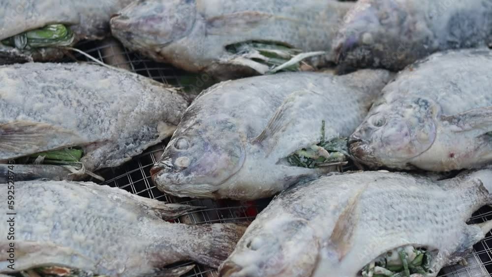 Salt-grilled fish is placed on a metal grill. Salt-grilled fish is placed on a metal grill.