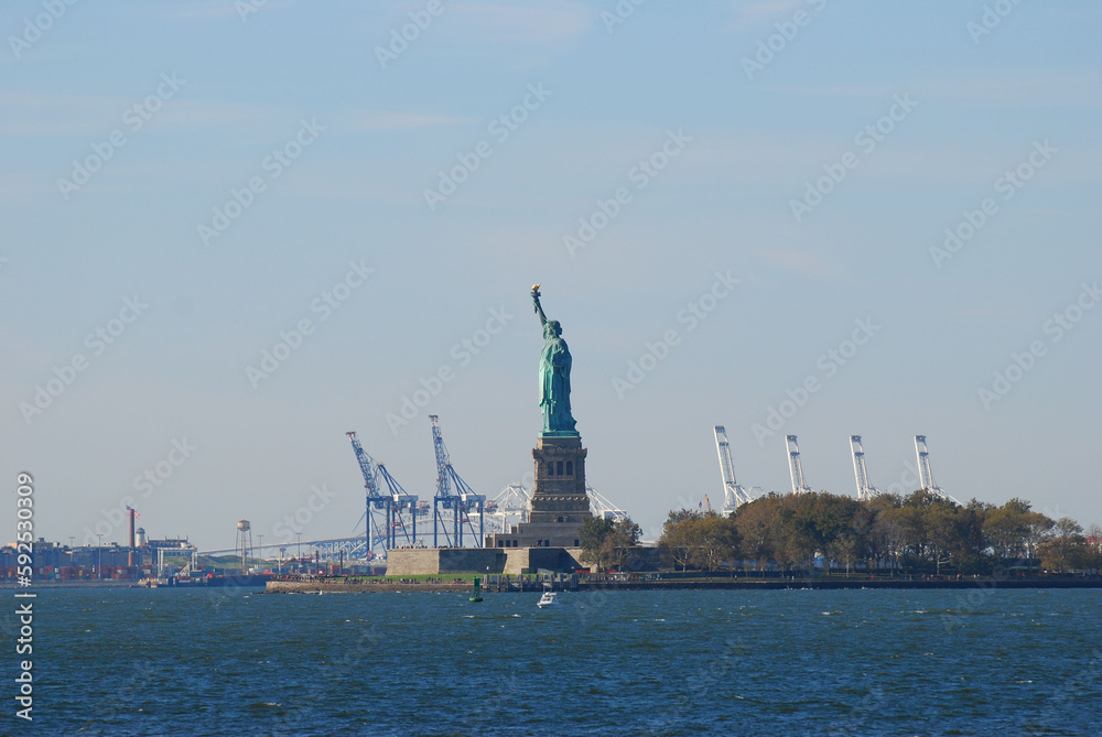 Statue of Liberty and Liberty Island with cranes in background in New York, USA