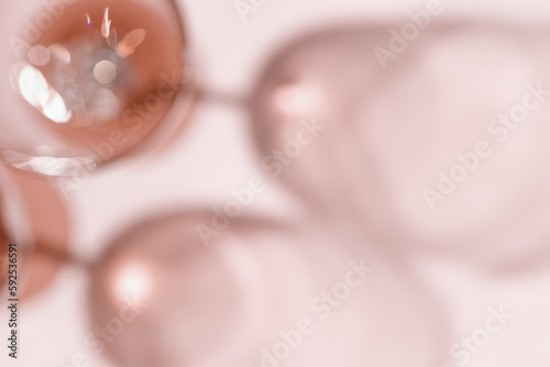 Wine glasses defocused, rose wine blurred on pink background with light flare, optical blur, bokeh. Top view aesthetic still life monochrome photo alcohol drink for winery, wine list