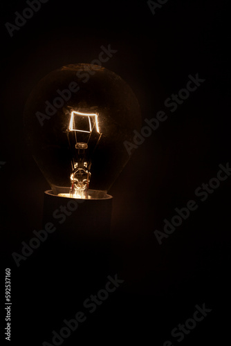 Single lightbulb glowing in the dark, South Africa load shedding