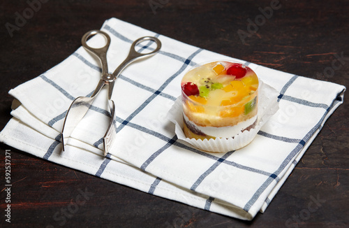 Cake with jelly, kiwi, cherries and mango on table. Yummy mini dessert on a wooden background, closeup
