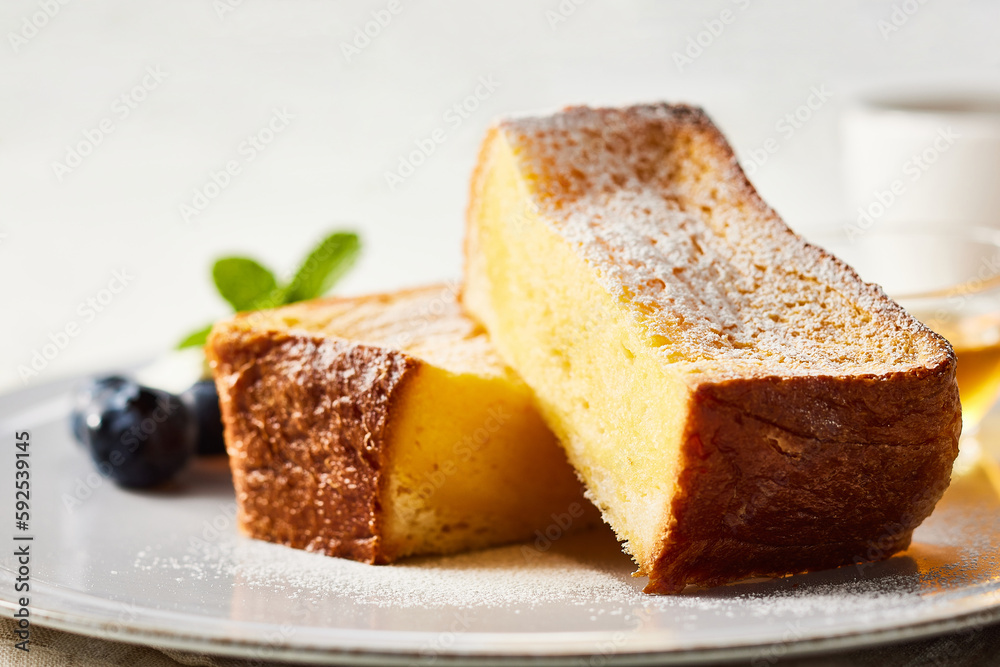 フレンチトースト お皿の上に生クリームとブルーベリーに蜂蜜を添えて。フォークとナイフ、コーヒーを白い木のテーブルの上に置いてます。 フレンチトースト お皿の上に生クリームとブルーベリーに蜂蜜を添えて。フォークとナイフ、コーヒーを白い木のテーブルの上に置いてます。