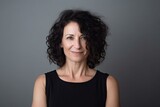 Smiling brunette woman, mid-aged, curly hair, arms crossed, grey background. Photo generative AI