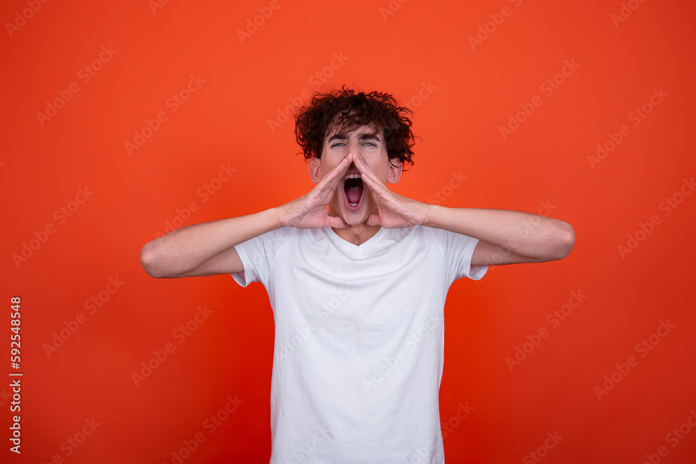 Young attractive guy posing in the studio. Emotional man. Orange background. Young attractive guy posing in the studio. Emotional man. Orange background.