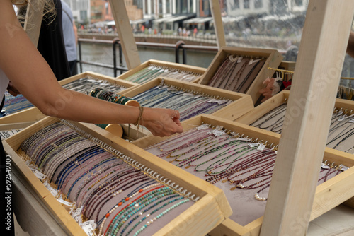 Jewelery showcase on street market. Woman choosing decorations on local street market in Gdansk, Poland. Female tourist is choosing souvenirs in street shop and looking at color bracelets. Candid