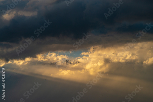 Beautiful dramatic sky with sunbeams through the clouds at sunset © vigenmnoyan