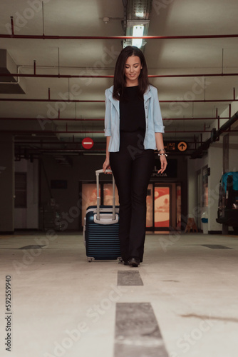 A business woman with a suitcase set in a modern garage while going to the airport. Business travel concept