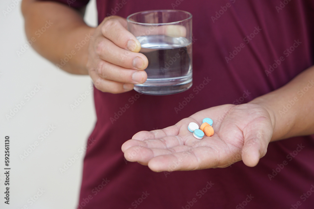Closeup hand holds glass of water to take medicine. Concept : Health care, health problem, sickness and remedy. Basic self take care , treatment at home when get sick. Take pills under prescription. Closeup hand holds glass of water to take medicine. Concept : Health care, health problem, sickness and remedy. Basic self take care , treatment at home when get sick. Take pills under prescription.
