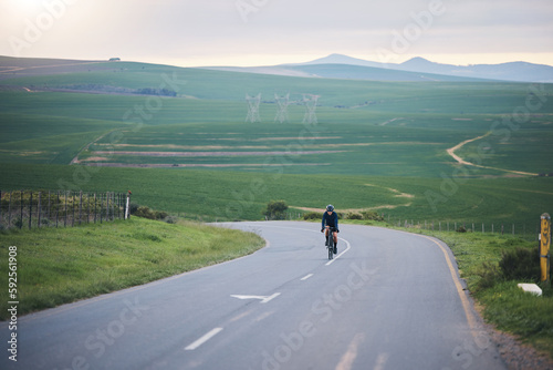 Fitness, nature and cyclist cycling on a mountain while training for a race, competition or marathon. Sports, health and athlete doing a cardio exercise or workout with bicycle in the road on a hill.