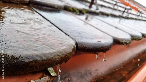 Close up of water falling down to gutter from the roof during heavy rain storm, slow motion footage clip