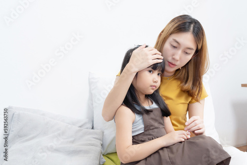 Asian mother hug her sick daughter on the bed with worry on her face