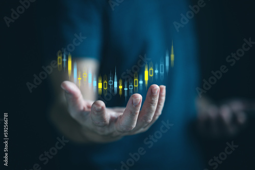 Businessman or trader is showing a growing virtual hologram stock above his hand, invest in trading. Stock market ,planning and strategy, Business growth, progress or success concept.