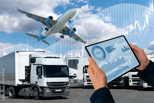 Manager with a digital tablet on a background of airplane and trucks. International trade and logistics concept 