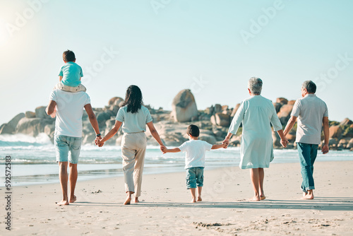 Holding hands, beach and rear view of big family walking at the sea, fun and travel on blue sky background. Behind, love and children with parents and grandparents on an ocean walk traveling in Miami